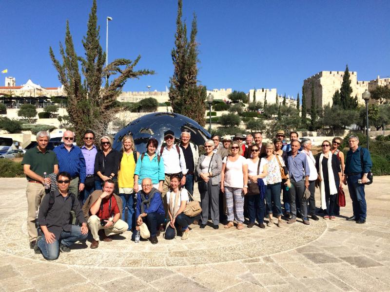 IF members gather in front of modern globe outside old walls of Jerusalem